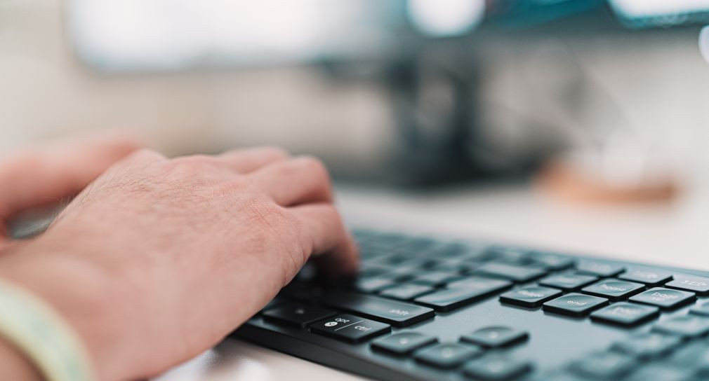 Eine Hand tippt auf einer Tastatur.