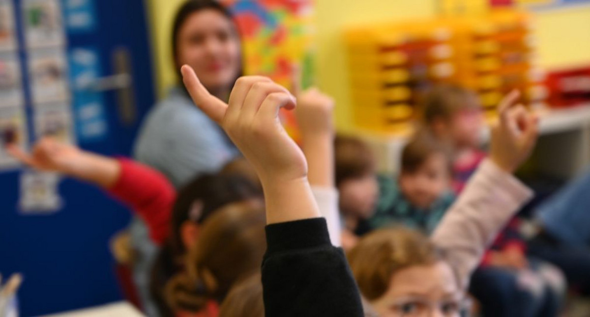 Ein sehr buntes Bild, bei dem man den oberen Teil von Kindern sieht, die den Arm hochstrecken