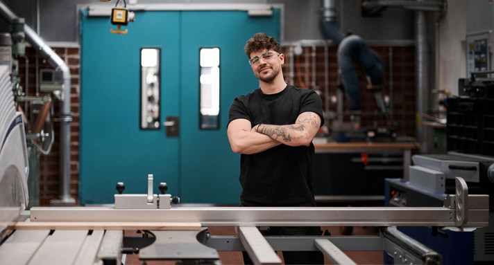 Ein Mann steht mit verschränkten Armen in einer Autowerkstatt.