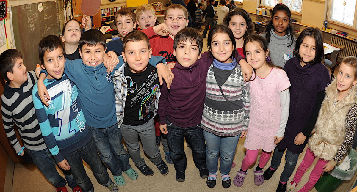 Eine Gruppe von Grundschulkindern steht eng bei- und nebeneinander und umarmt sich über die Schultern