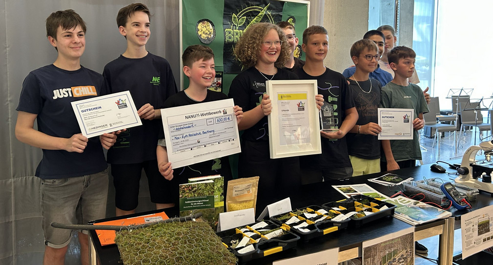Gruppenbild der Gewinnerinnen und Gewinnern des NANU?!-Wettbewerbs 2026 mit ihren Preisen an ihrem Stand.