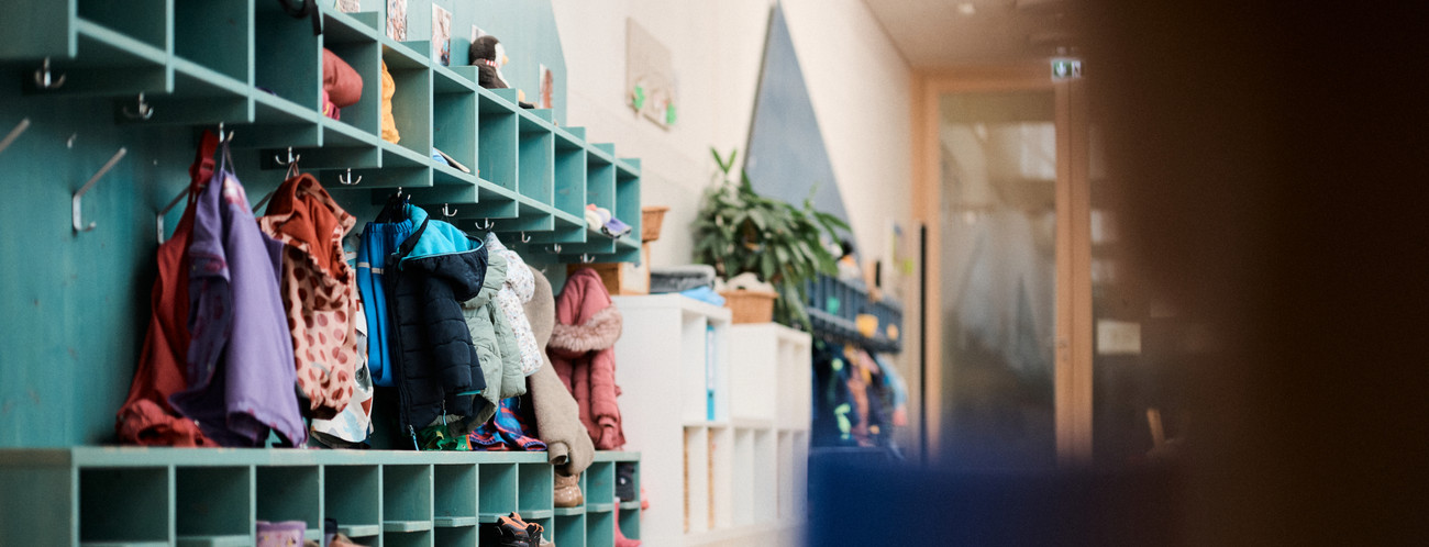 Ein Garderobe mit vielen Kinderjacken und Taschen. 