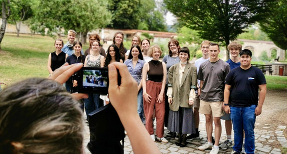 Eine Gruppe von Jugendlichen steht vor einer Wiese.