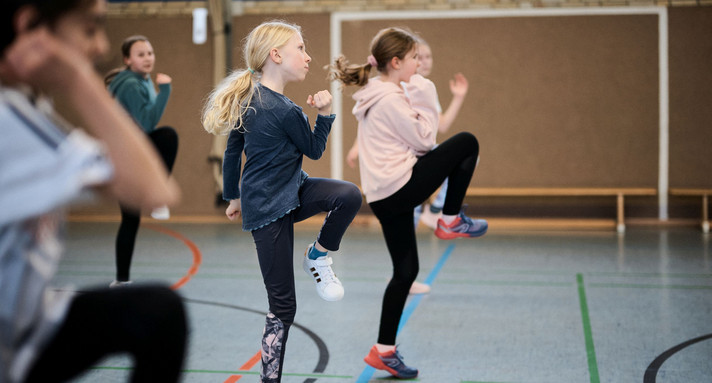 Mehrere Kinder machen in einer Sporthalle Gymnasik-Übungen.