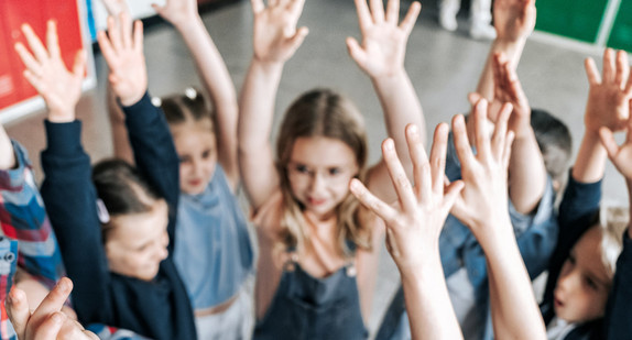 Kreis von Kindern, die die Arme nach oben strecken