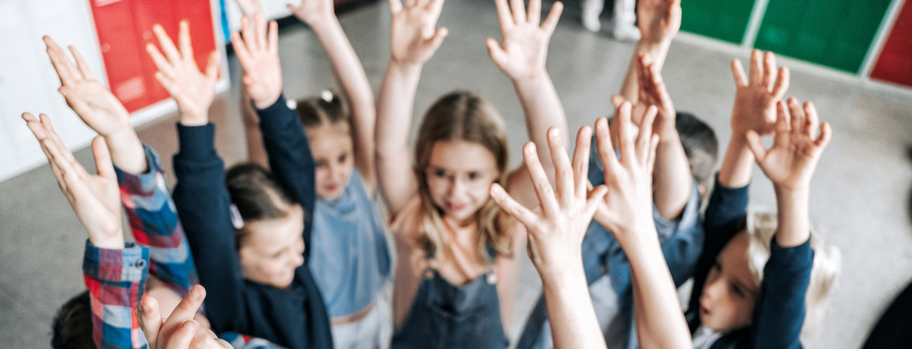 Kreis von Kindern, die die Arme nach oben strecken