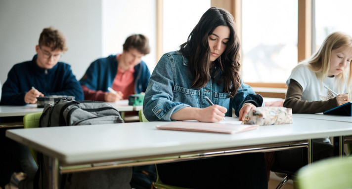 Eine Klasse sitzt im Klassenzimmer und arbeitet an Aufgaben