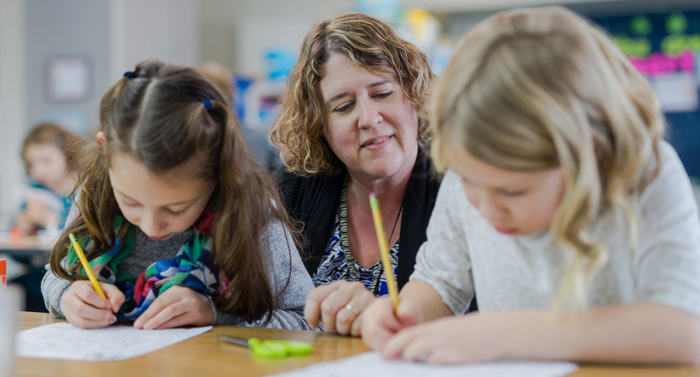 Lehrerin hilft jungen Schülerinnen an ihrem Arbeitsplatz