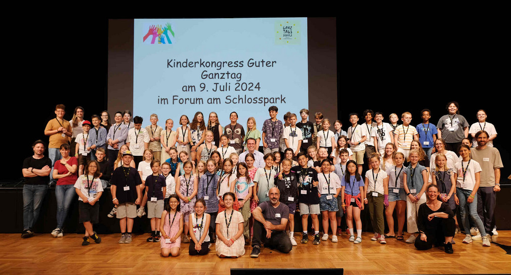 Gruppenfoto von Grundschülerinnen und -schülern auf der Bühne in einem Veranstaltungssaal